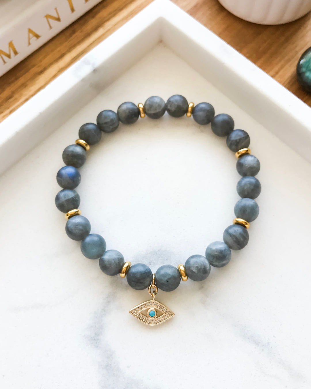 A mala bracelet made with matte labradorite beads and gold-colored accents, displayed on a white surface.